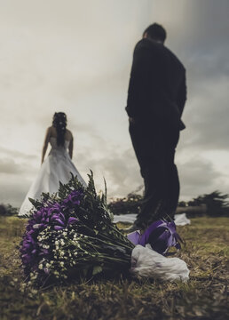 Una paraje recien casada, novios, esposos y un ramo de flores , mirando al atardecer