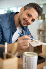 man painting handmade pottery at ceramic workshop