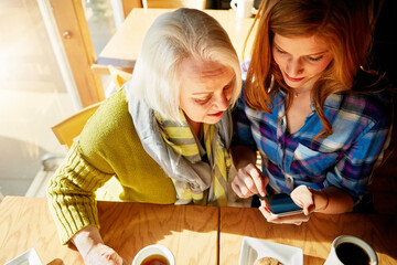 Senior woman, daughter and smartphone and in cafe for social media learning, post or coffee shop....