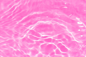 Pink water bubbles on the surface ripples. Defocus blurred transparent pink colored clear calm water surface texture with splash and bubbles. Water waves with shining pattern texture background