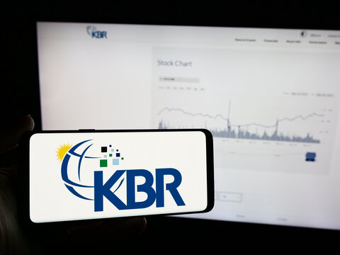 Stuttgart, Germany - 05-27-2024: Person holding mobile phone with logo of American engineering and construction company KBR Inc. in front of web page. Focus on phone display.