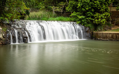 A waterfall taken with long exposure as it plunges into a swimming hole at a popular tourist attraction in the town of Malanda on the Atherton Tablelands in tropical Queensland, Australia.