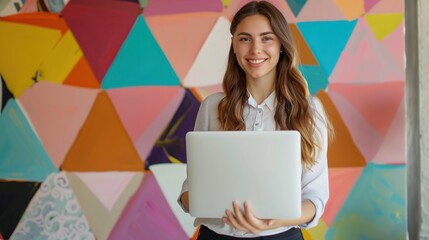 Cheerful businesswoman standing while using laptop in office