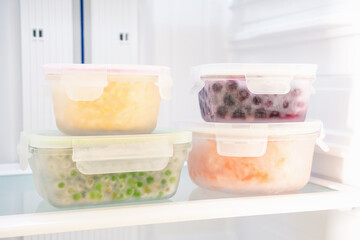 Vegetables and berries in glass boxes in the freezer close-up.