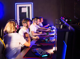 Coach and team wins round game in E-sport cyber tournament. Gamers play video game on PC at computer club. Tactics strategy trainer. 5 Caucasian players in headset. Happy emotions. High-five gesture © HENADZY
