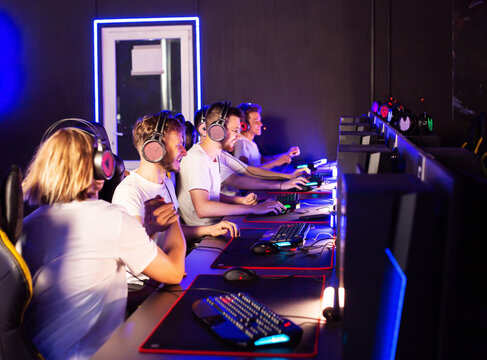 Coach and team wins round game in E-sport cyber tournament. Gamers play video game on PC at computer club. Tactics strategy trainer. 5 Caucasian players in headset. Happy emotions. High-five gesture