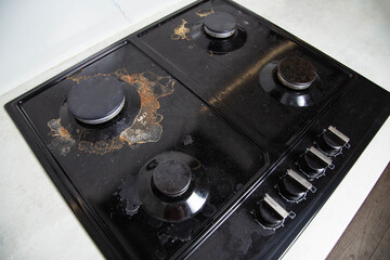 Dirty built-in black gas stove with scale and carbon deposits. Cleaning from scale and grease,...