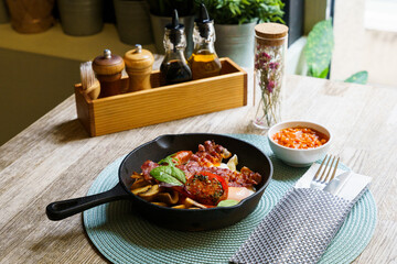 English Breakfast in cooking pan with fried eggs, sausages, bacon, mushrooms, beans and tomato