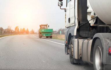 Wheels and a projector on the tires of a truck on the road in front of a tractor creating an...