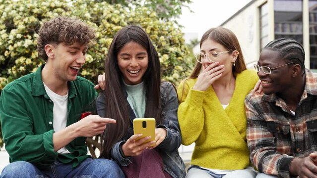 Young friends sitting together using mobile cell phone to share funny content on social media app