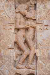 A stone carving of man and woman kissing on a wall is found in an archaeological site of Mandakini Temple