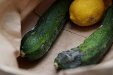 Close up of rotten zucchinis and a lemon in a paper eco bag