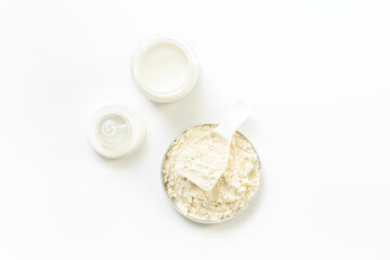Milk for baby in a bottle with powdered milk in a spoon on white background, top view