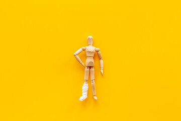 Wooden dummy man with leg broken - leg in bandage. Medical insurance and healthcare concept