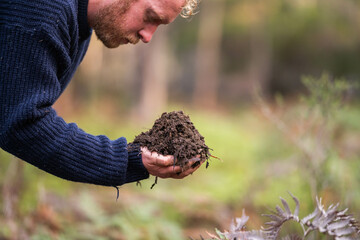 farmer collecting soil samples in a test tube in a field. Agronomist checking soil carbon and plant health on a farm in  a field