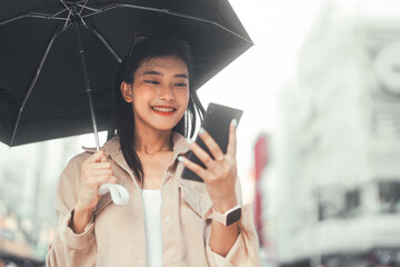 Youth asian woman using smartphone and umbrella at outdoor
