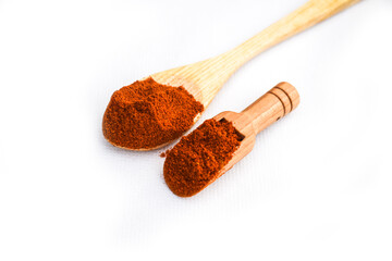 red chilli  in spoon, Pile of red paprika powder in wooden spoon isolated on white, top view,...