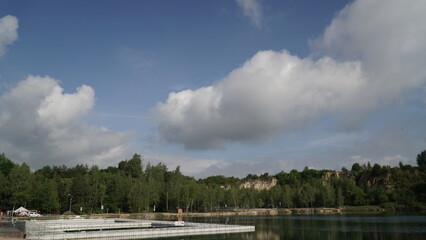 Lake with Segregated Swimming Pools under Blue Sky and Clouds A serene lake scene showcases segregated swimming pools, each delineated for different activities, against the backdrop of a clear blue sk