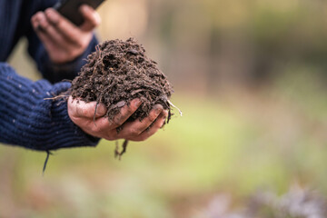 farmer collecting soil samples in a test tube in a field. Agronomist checking soil carbon and plant health on a farm in  a field