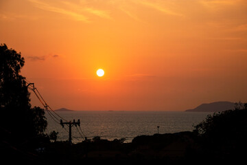 Obraz premium The sun is setting over the ocean, casting a warm glow over the water