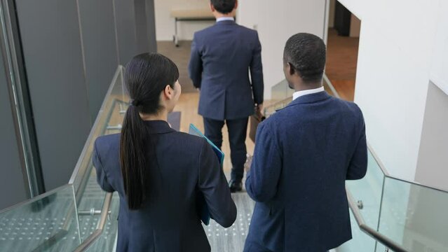 ビルの中を歩きながら会話する多国籍ビジネスパーソンのグループ