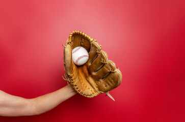 Female baseball gloved hand catches ball. Red background. Active sport, championship, victory.