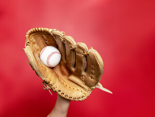 Leather baseball glove with white baseball on female hand on red background. Quality photo. Winner.