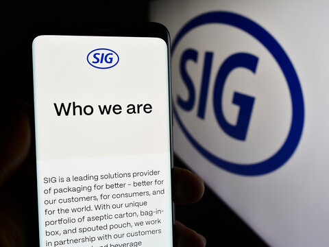 Stuttgart, Germany - 05-31-2024: Person holding smartphone with webpage of Swiss packaging company SIG Group AG in front of business logo. Focus on center of phone display.