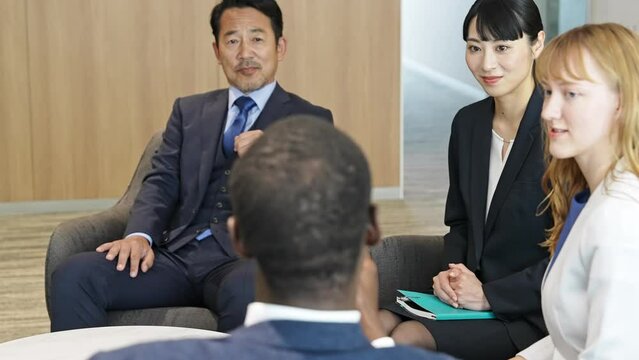 ロビーで会話する多国籍ビジネスパーソンのグループ