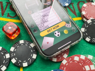 online casino smartphone with poker chips device over green table