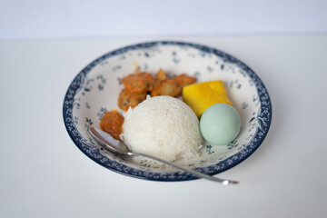 A lunch plate featuring rice, tofu, eggs, and jengkol, showcasing a traditional and flavorful meal