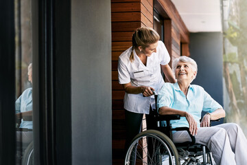 Nurse, talking and senior woman on wheelchair for support or rehabilitation of medical healthcare patient. Happy caregiver, retirement or person with disability at home for recovery, wellness or help