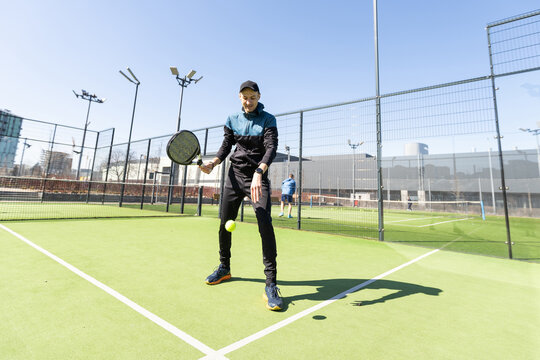 Young padel player trains by catching high balls