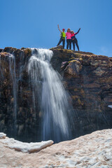 Obraz premium Happy Hikers Standing on Cliff with Waterfall