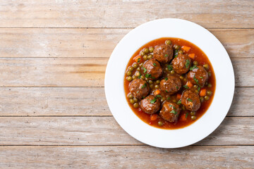 Meatballs, green peas and carrot with tomato sauce on wooden table. Top view. Copy space