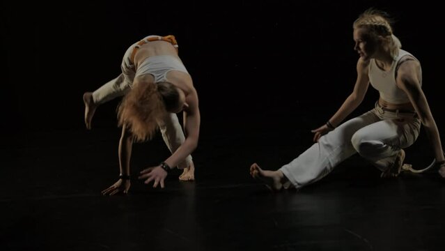Capoeira fighters performing dynamic moves on stage. Martial arts, dance, and acrobatics in action. Bare-chested athletes showcasing strength, flexibility, and technique under spotlights