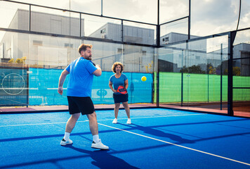 Obraz premium Mixed adult couple playing padel on outdoor court.