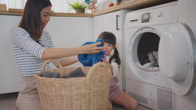 Asian beautiful mother teach young daughter wash dirty clothes at home. 