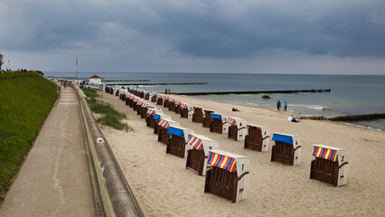 Obraz premium Blick von der Strandpromenade auf ordentlich aufgereihte Strandkörbe am Ostseestrand von Kühlungsborn bei bewölktem Himmel, Mecklenburg-Vorpommern, Deutschland