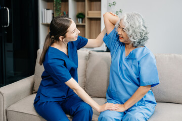 Physiotherapist helping elderly woman patient stretching arm during exercise correct with dumbbell...