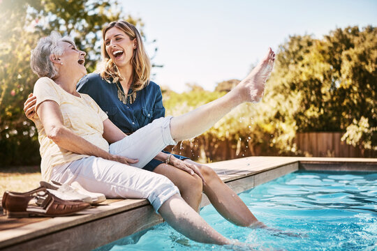 Mother, daughter and happiness by swimming pool for wellness, hug or relax with lens flare in garden. Senior mom, woman and outdoor with smile for bonding, family with embrace or love and foot in air