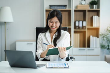 Cheerful young woman taking notes while working in the office, Happy woman, entrepreneur, small business owner working online.