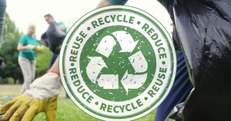 Fototapeta premium Image of recycling icon over volunteers cleaning in park