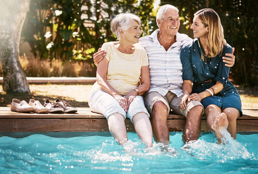 Happy, family and hug in pool together outdoor, bonding and conversation on summer holiday with trust and care. People, senior parents and daughter with love embrace for wellness and reunion at home