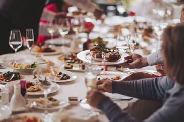 Waiter serving table in the restaurant preparing to receive guests. Waiter carrying plates with meat dish on some festive event. 