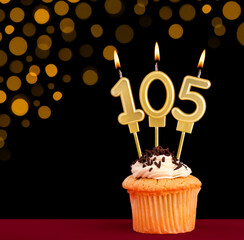 Birthday candle with cupcake - Number 105 on black background with out of focus lights