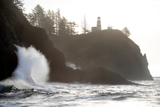 Waves crashing onto rocks along the shore below Cape Disappointment Lighthouse, Waikiki Beach, Cape Disappointment State Park, Washington, USA. January, 2023. 
