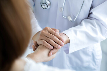 The female doctor uses a friendly hand to hold the patient's hand to give confidence and show care about health care. Medical concepts and good health