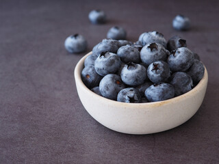 Organic ripe fresh blueberries in bowl on dark grey stone background. Concept for healthy eating and nutrition, space for your text. Superfood..
