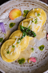 Tortelloni di pasta fresca ripiena alla Nerano con zucchine e provolone del monaco conditi con burro e scaglie di provolone del monaco serviti in un ristorante elegante